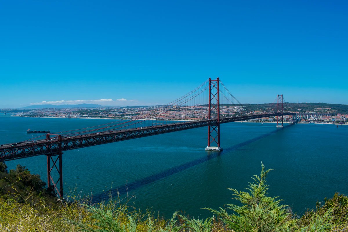 Lisbon’s red 25 de Abril Bridge above the blue Tagus River, with the city on the far bank